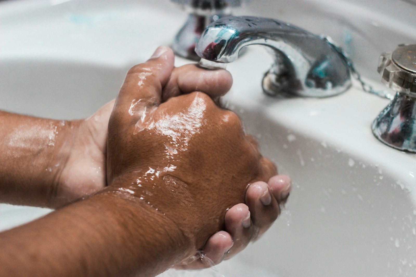Hands being washed with soap at a sink