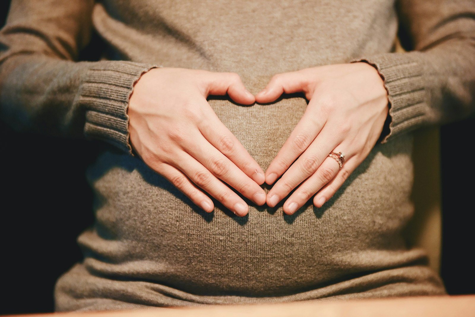 A pregnant person resting a hand on their abdomen