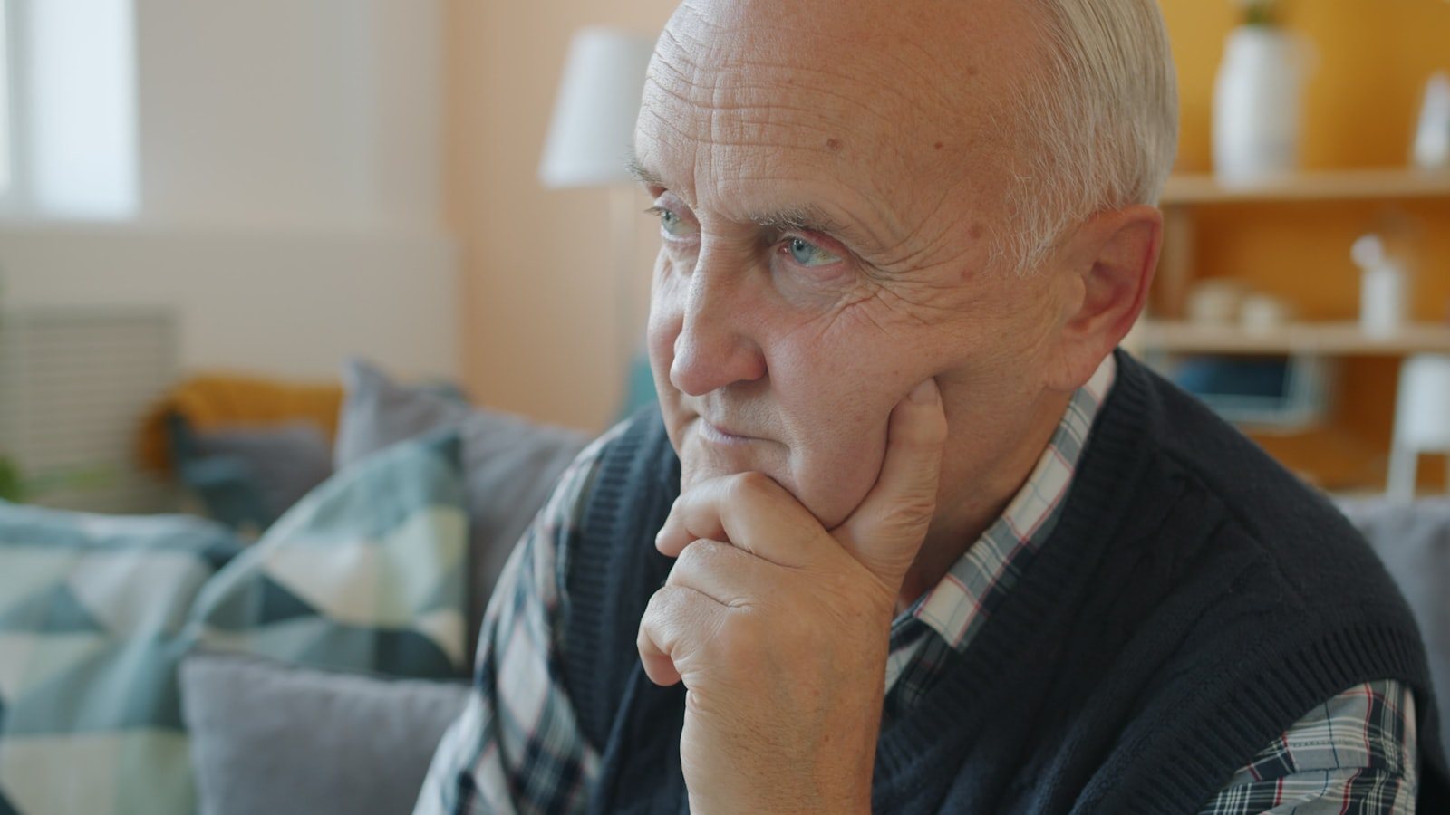 An older person sitting at home in discomfort