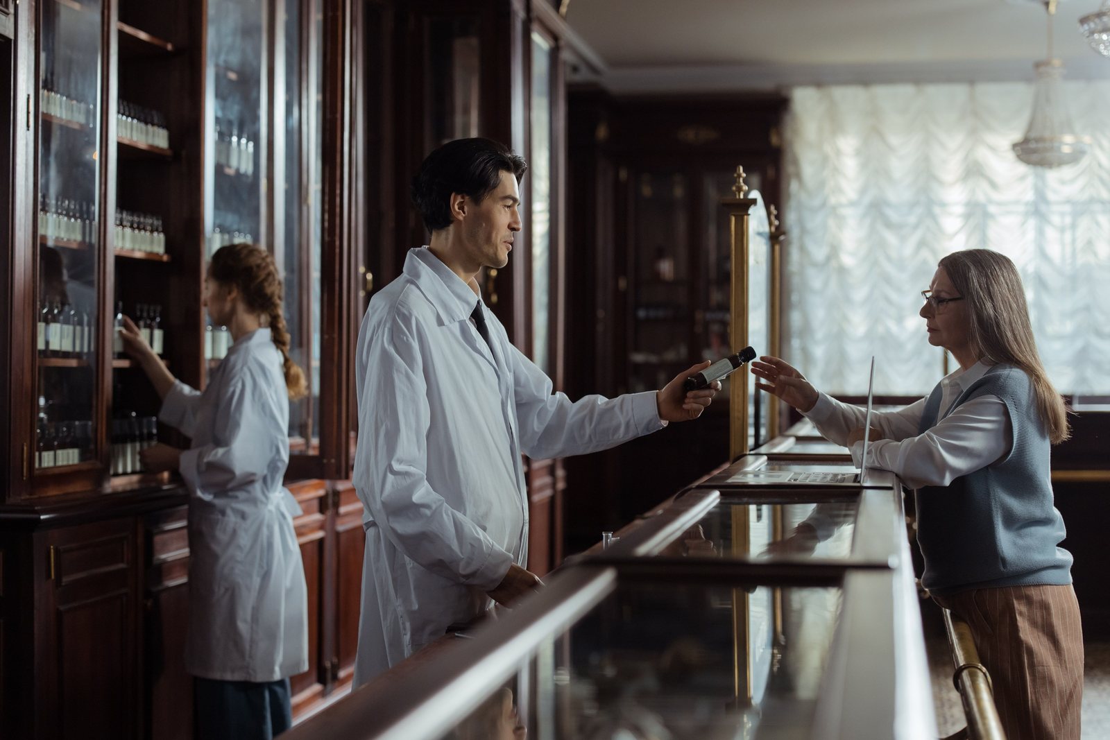 A pharmacist handing medication to a customer at a counter