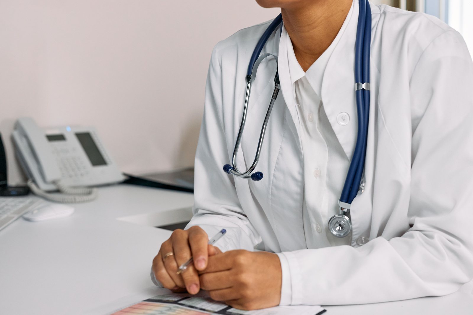 A clinician seated at a desk with a stethoscope