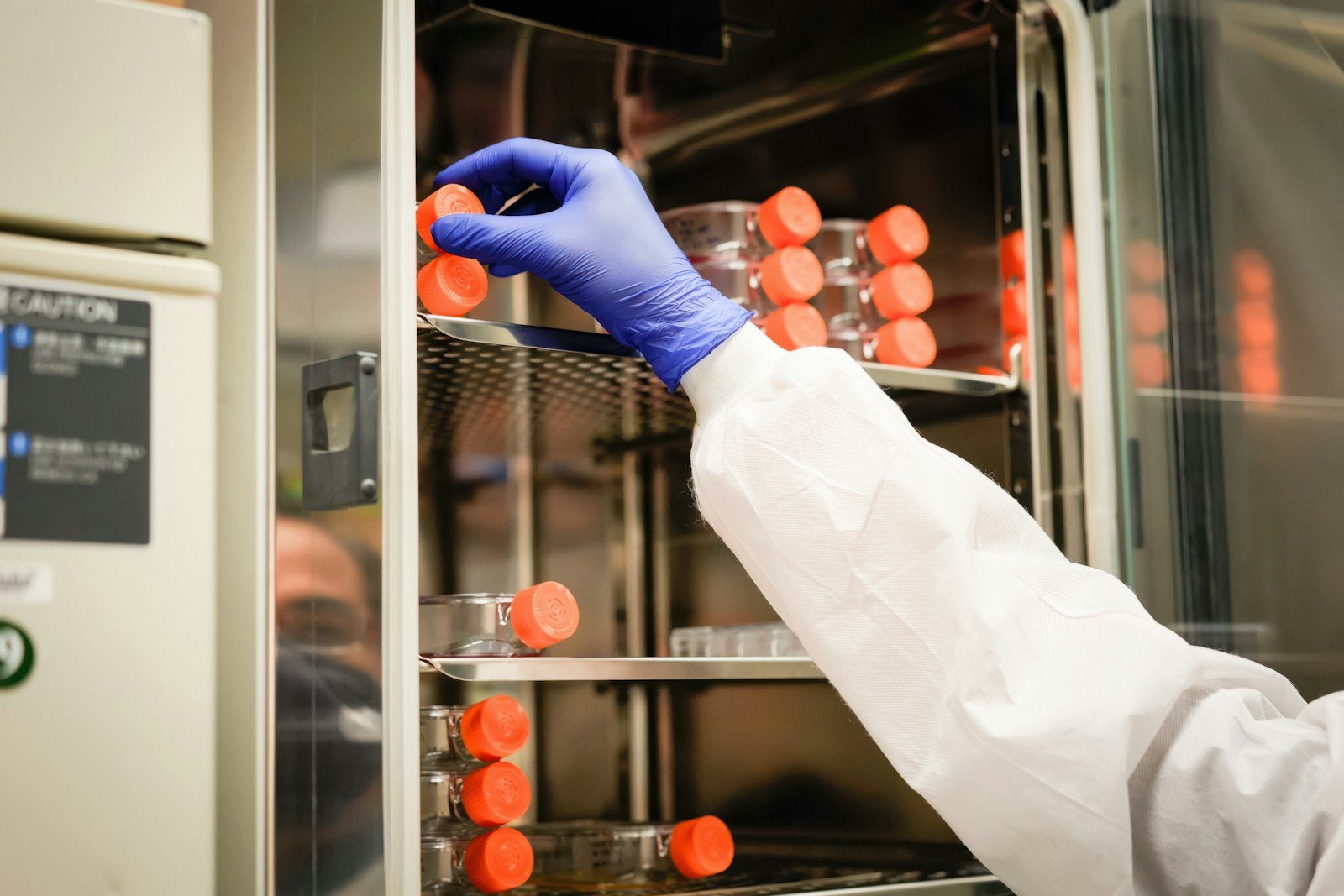 A gloved hand placing sample tubes into a laboratory unit