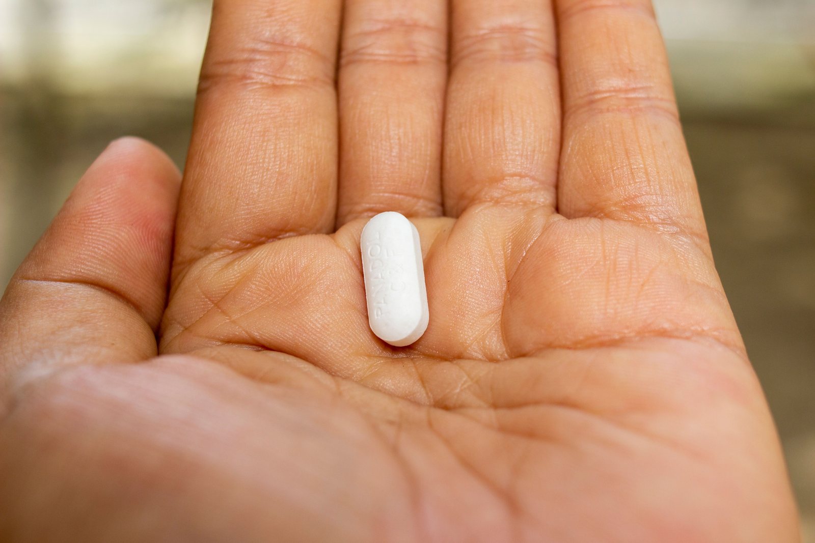 A single white tablet in the palm of a hand