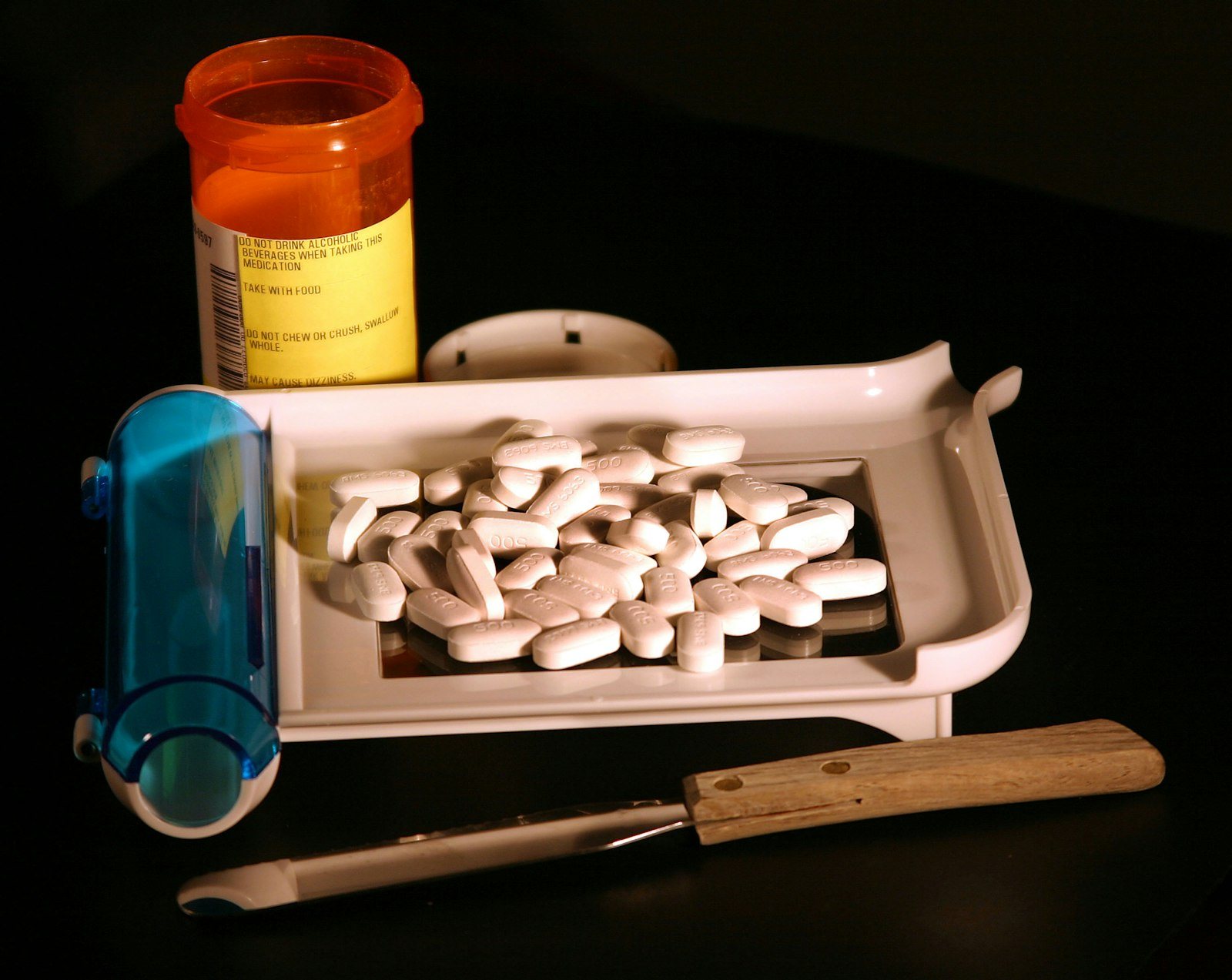 Tablets on a pharmacy counting tray beside a prescription bottle