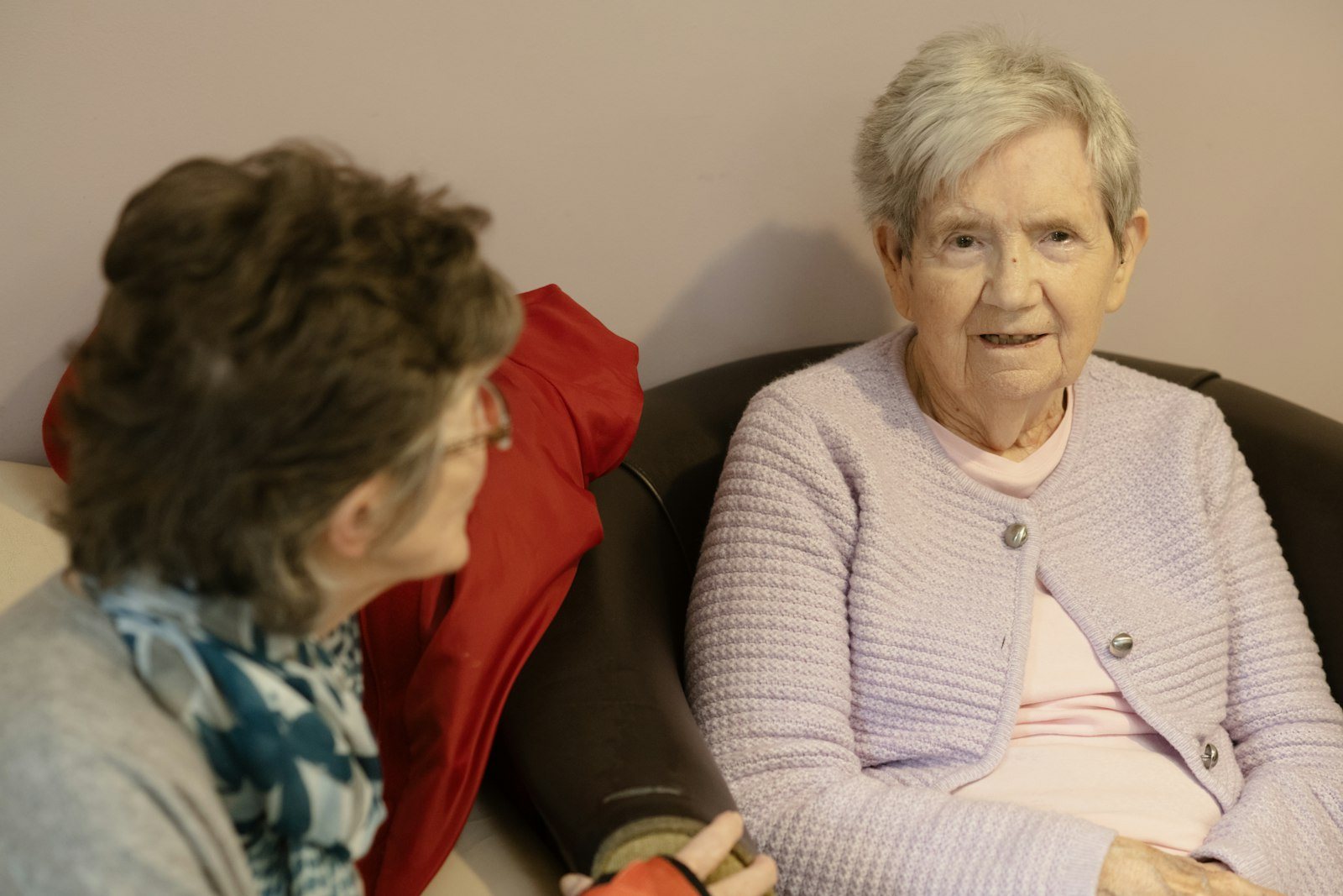 An older adult sitting at home with a family member