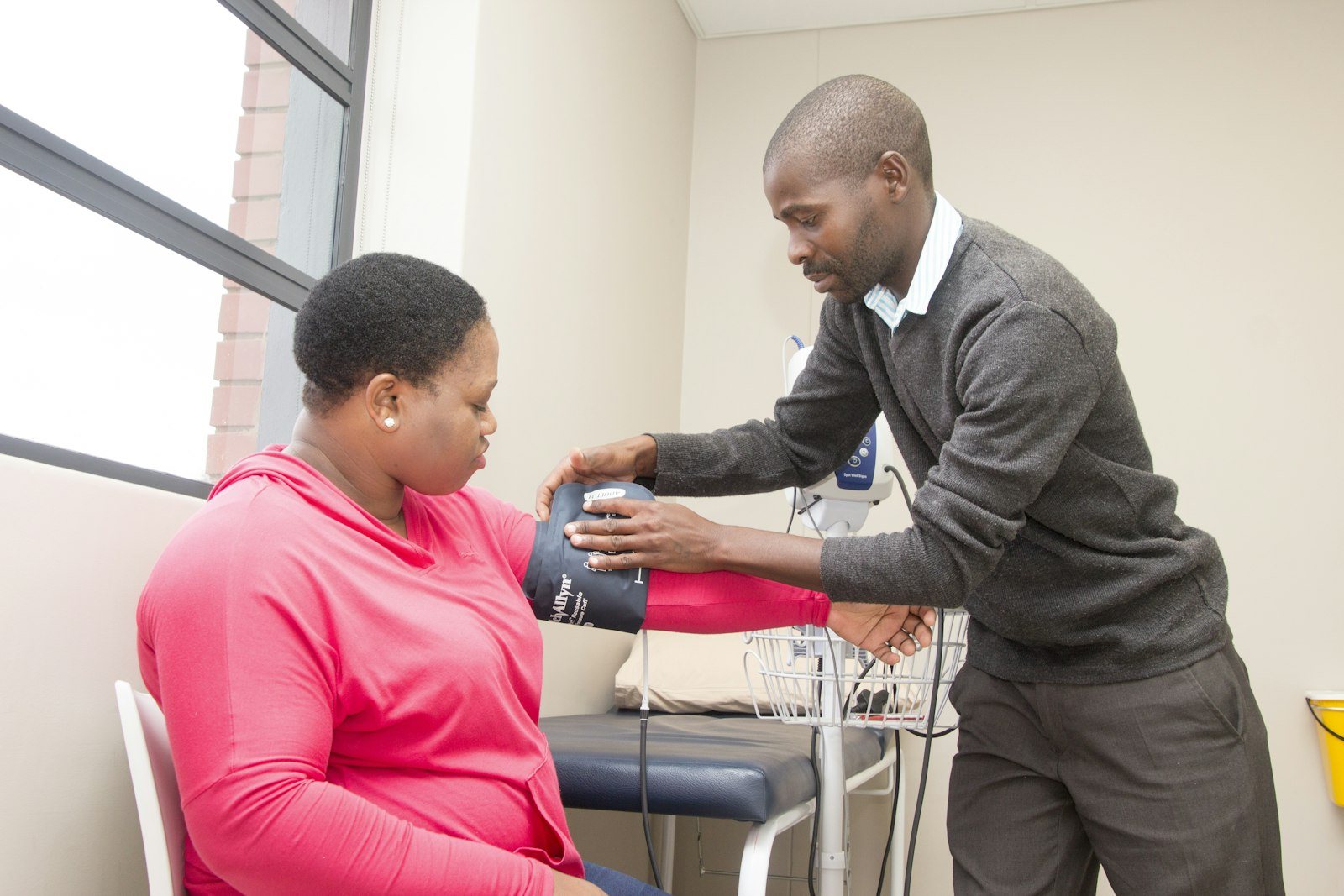 A blood pressure cuff being fitted to a patient arm in a clinic