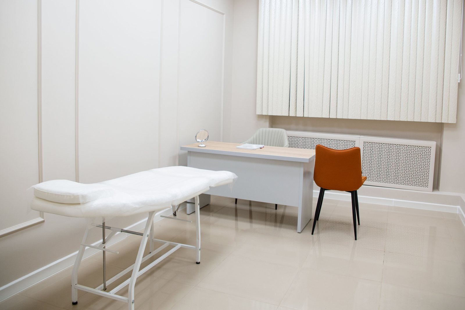 A quiet medical examination room with a desk and chairs