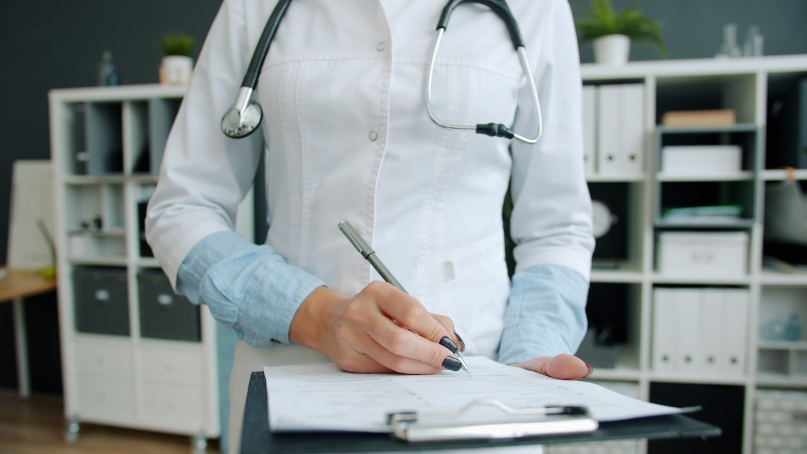 A clinician writing notes on a clipboard